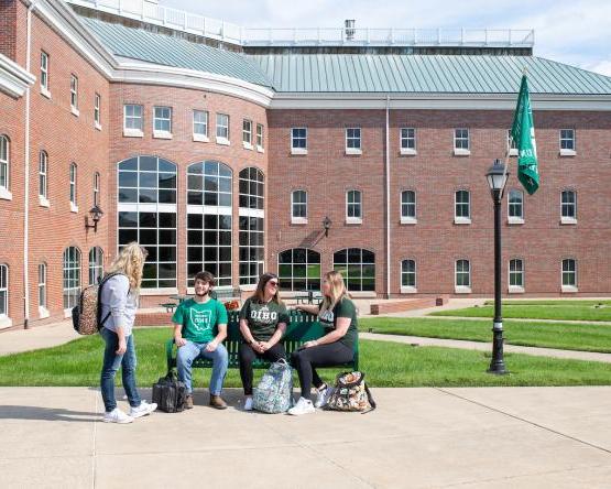 Four OHIO students talk outside on campus.