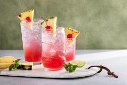 tropical cocktails topped with pineapple and cherries